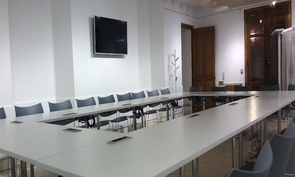 grande table en U fermée avec un écran au mur