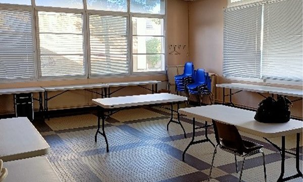 petite salle avec des tables et des fenêtres sur les deux murs